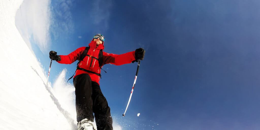 Skier in mountains performs a high speed turn on a ski piste